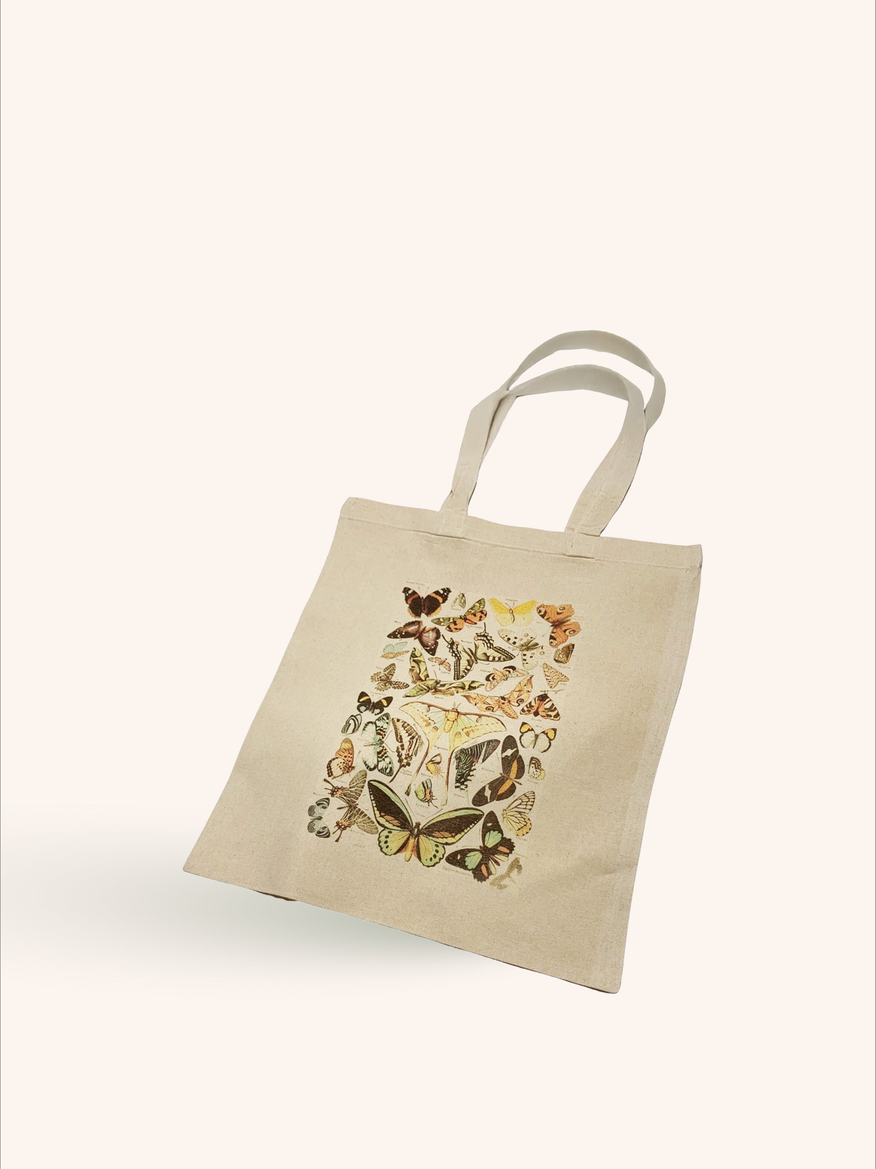 A beige tote bag with a vintage floral print in the center, displayed against a white background.