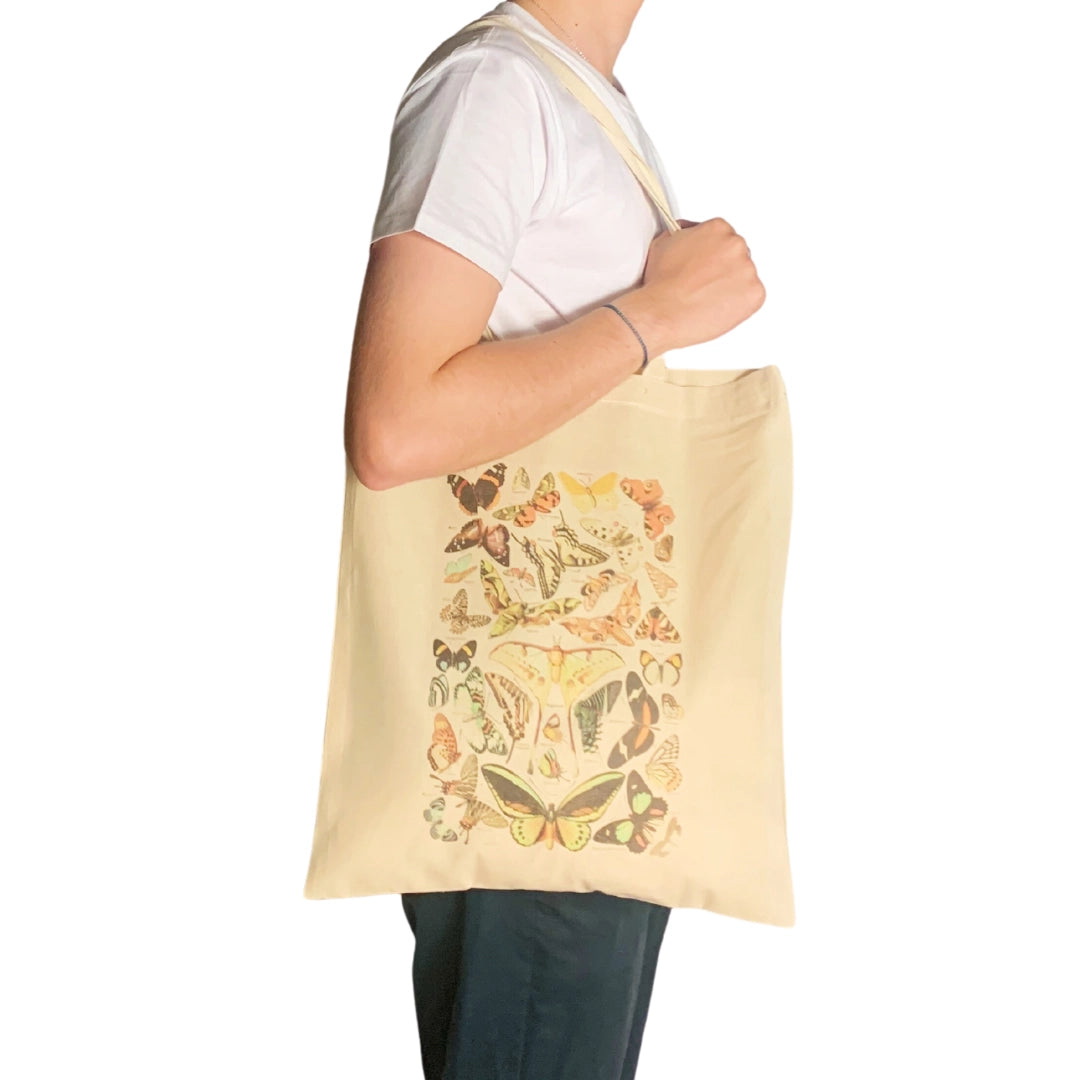 Person holding a beige tote bag with butterfly design.