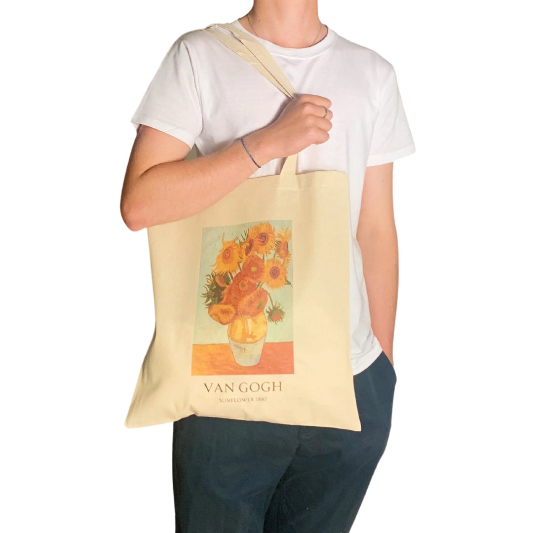 Person holding a tote bag with a Van Gogh painting of sunflowers.